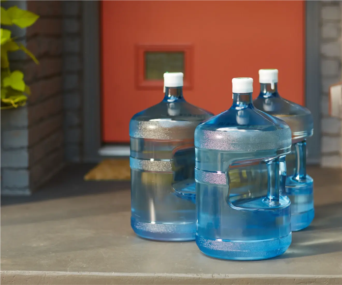 Three water dispenser jugs on a front door step