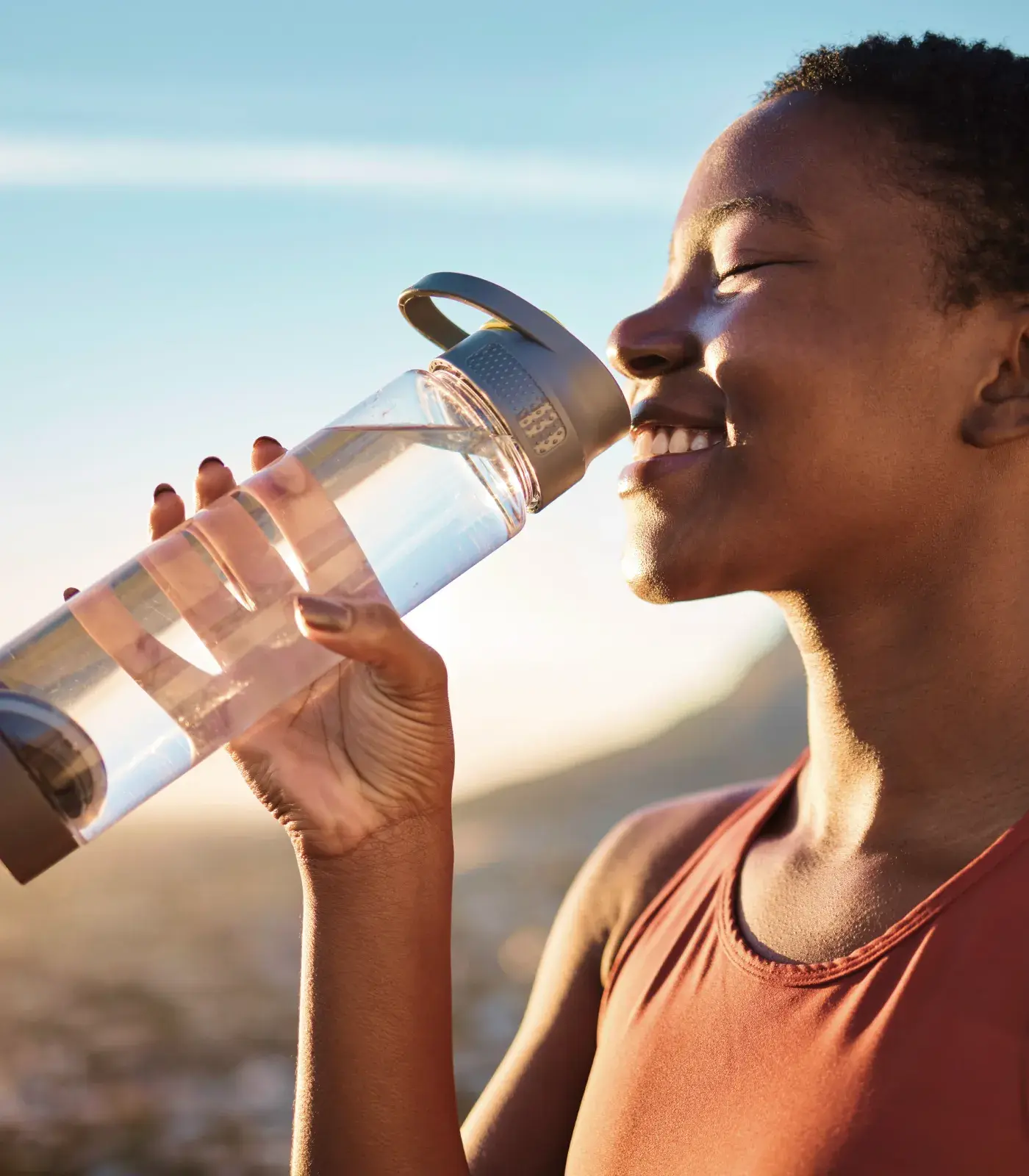 A woman enjoying Primo Water from a resuable bottle