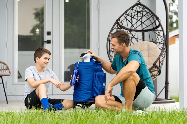 Father and son use a rolling cooler water dispenser on the back patio